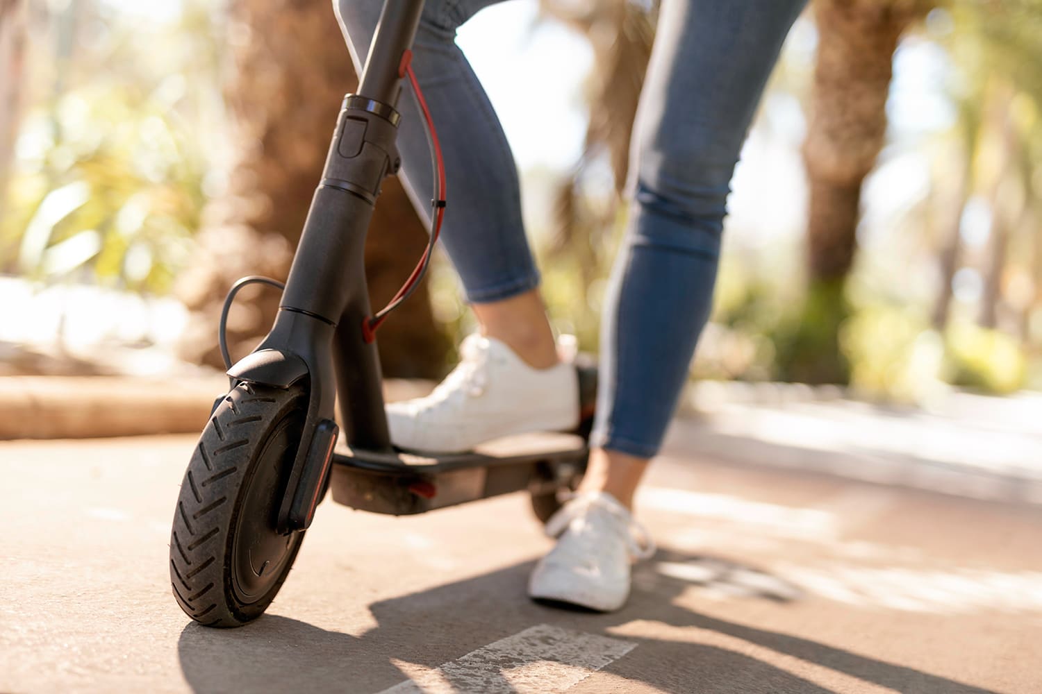 unos pies de mujer sobre un patinete eléctrico