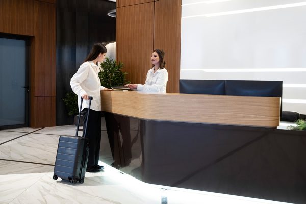 una recepcionista atiende a la huésped de un hotel