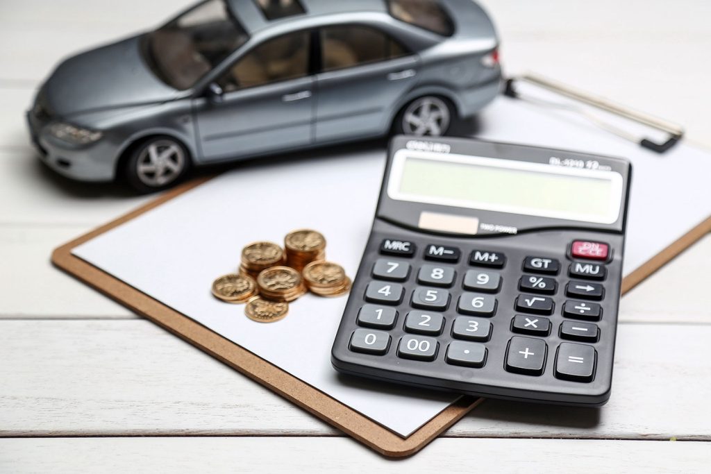 una calculadora junto a un coche y unas monedas