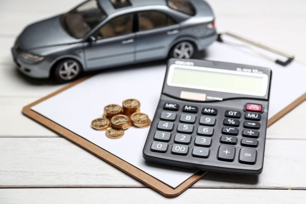 una calculadora junto a un coche y unas monedas