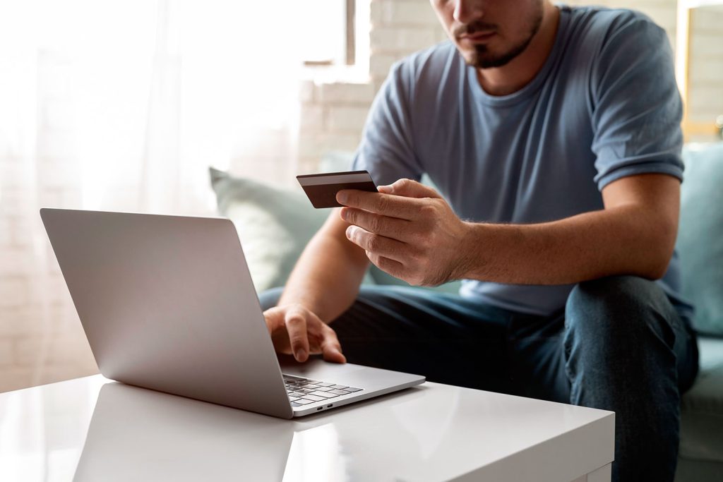 un hombre se dispone a hacer un pago online con su ordenador portátil