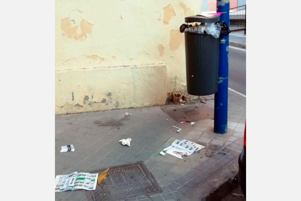 una papelera llena en Leganés y suciedad en el suelo