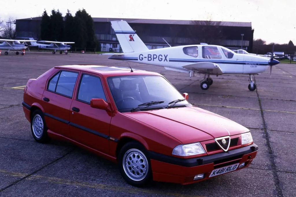 Alfa Romeo de color rojo junto a un avión