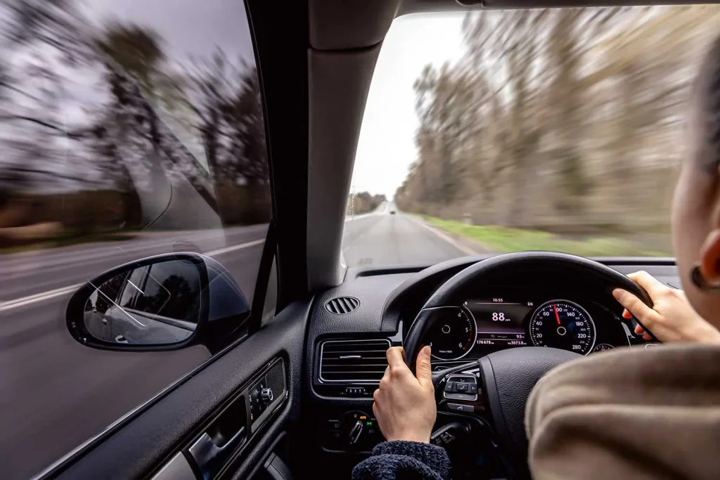 una mujer conduce un automóvil por carretera a una velocidad de 88 km/h